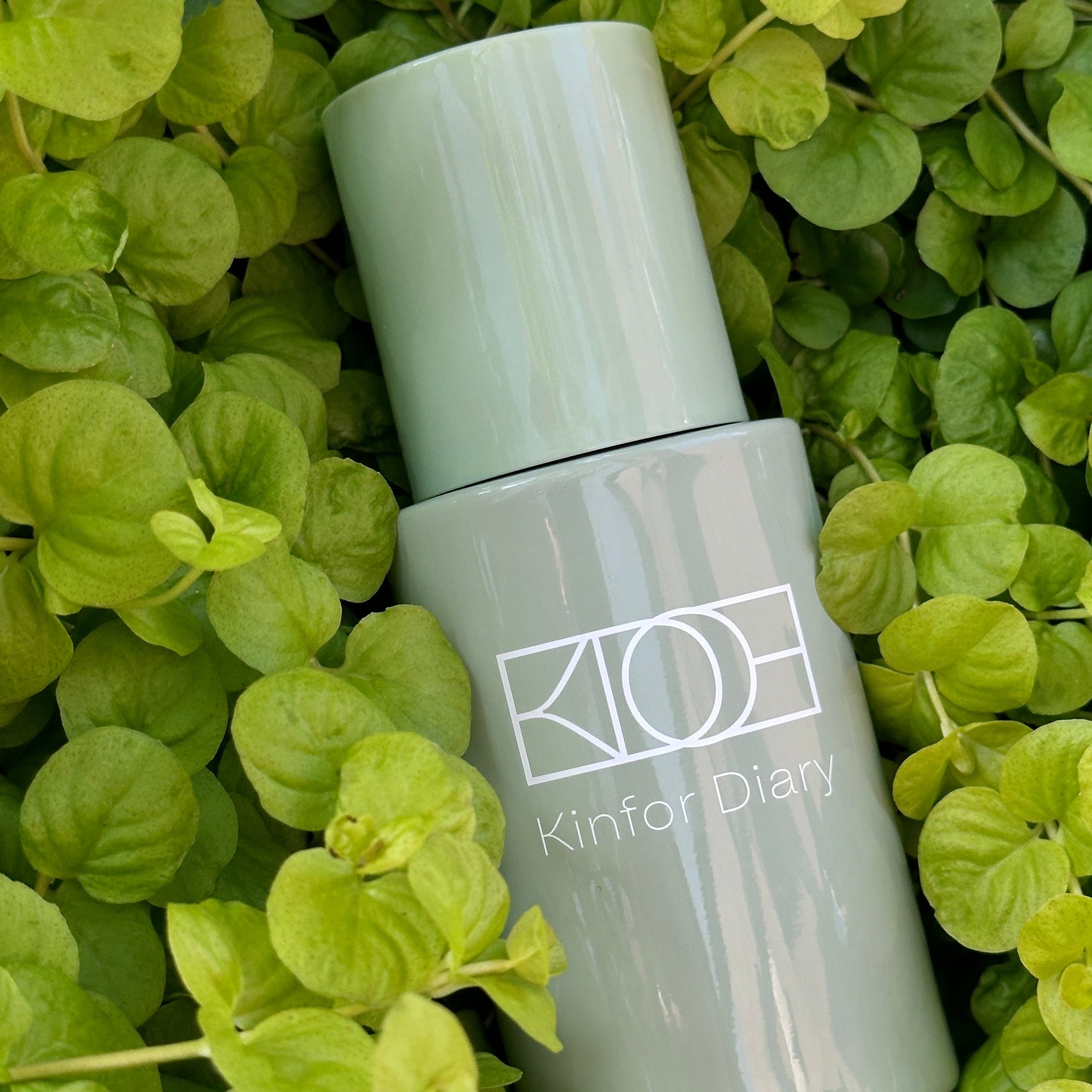 Skincare bottle with 'KINFOR DIARY' branding on a green leaf background