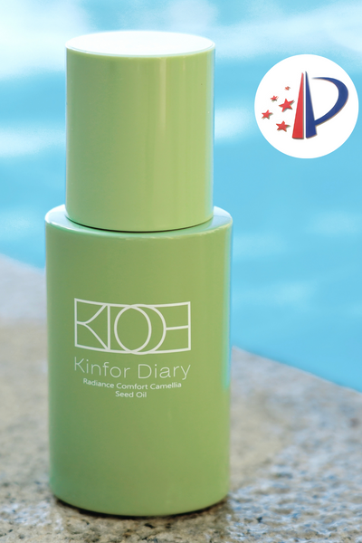 Green bottle labeled 'Kinfur Diary' on a beach with a blurred background
